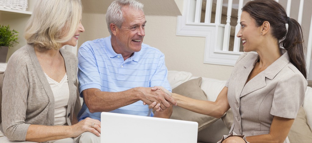 Saleswoman Shaking Hands With Senior Couple at Home